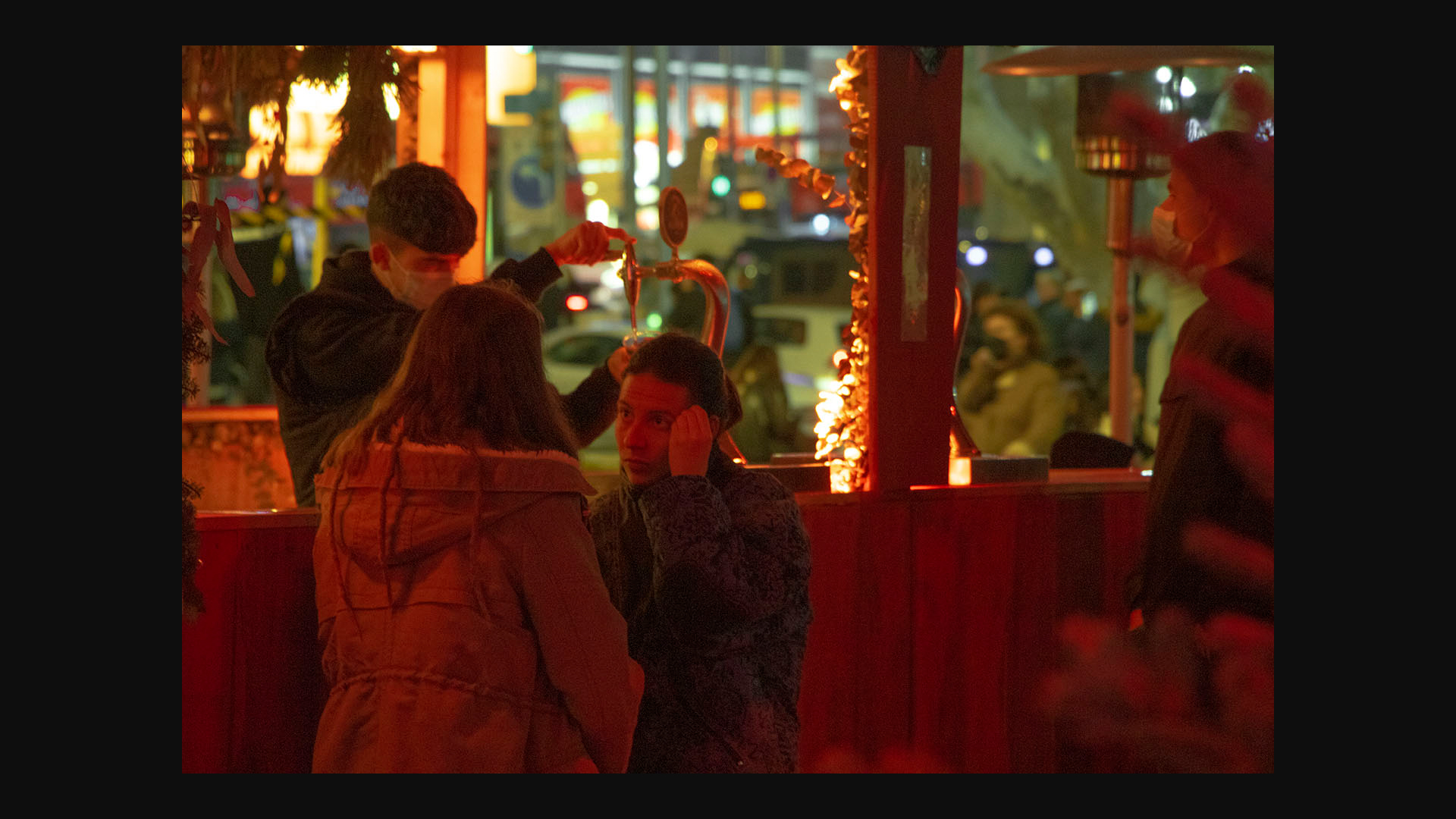 La última imagen muestra a dos chicas hablando en uno de los puestos de comida navideños de Plaza España, una de ellas con una mueca de preocupación. Mientras, detrás, un camarero sirve una cerveza.